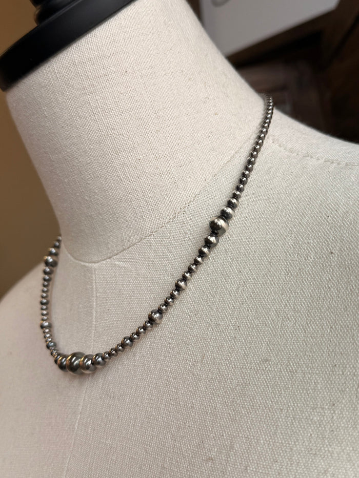 Graduated sterling silver bead necklace detail with round bead links along chain