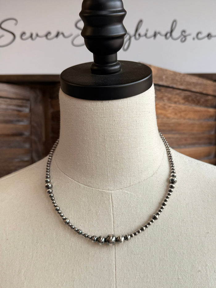 Graduated sterling silver bead necklace with evenly spaced beads, full length on mannequin