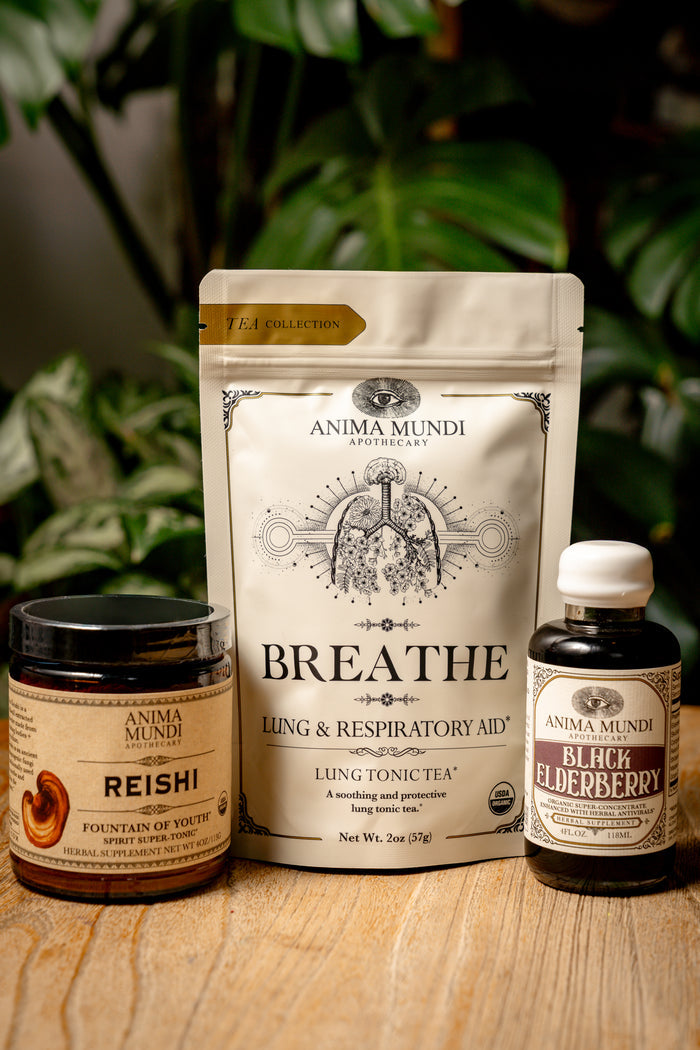 Anima Mundi health products including a jar, pouch, and bottle on a wooden surface with plants in the background.