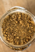 Close-up of a glass jar filled with dried herbs on a wooden surface