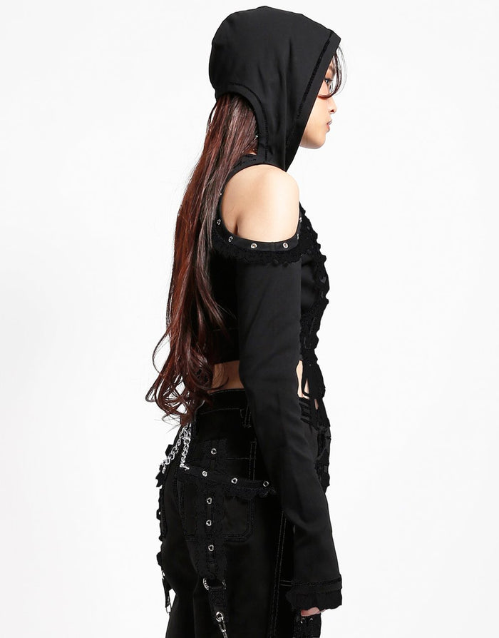 side of Black hoodie with gothic Lolita details. Hoodie has long sleeves that have thumb holes and black lace around the hands. Shoulders are open, and have edges of black on black lace details, as well as silver rivet details around the edge. Front of hoodie zips up, and has black on black lacey lace-up panels on right and left of zipper. Hoodie has black hood.