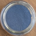 Close-up of a glass jar filled with blue powder on a wooden surface