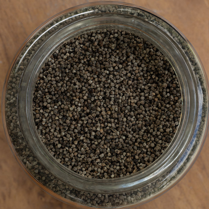 Close-up of a glass jar filled with small brown pellets on a wooden surface.