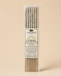A package of Anima Mundi White Copal incense sticks, featuring a clear plastic sleeve with a central cream-colored paper label, set against a solid beige background.