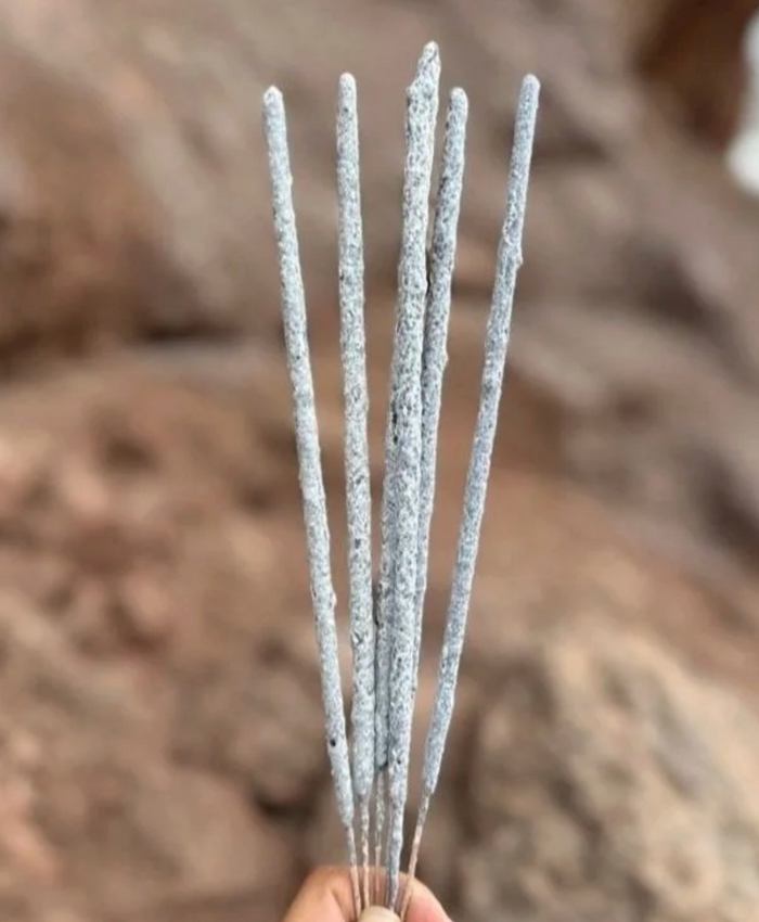 Silver incense sticks held against a blurred brown background