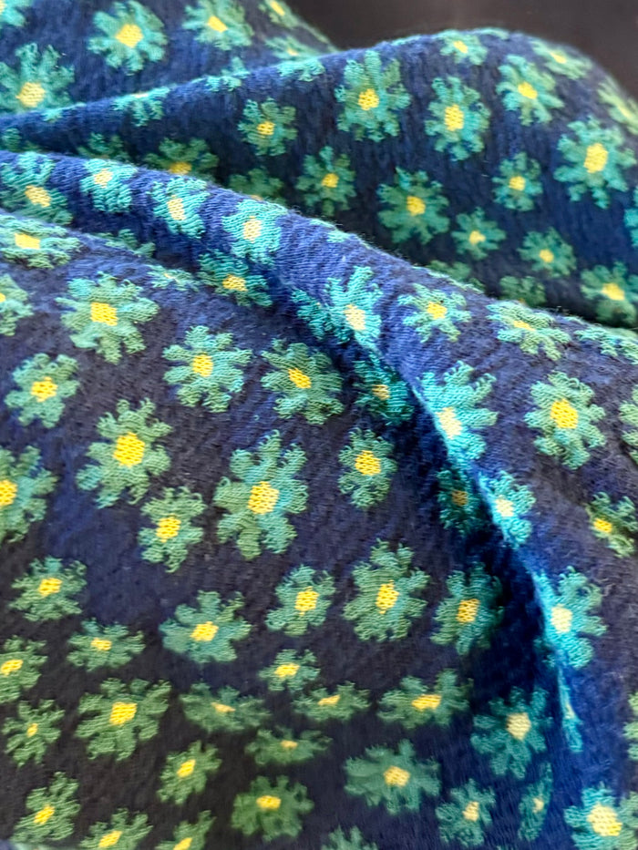 Close-up floral waffle knit fabric in dark blue with green and yellow star-like flowers