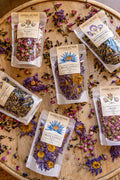Anima Mundi tea packages on a wooden surface with dried flowers.