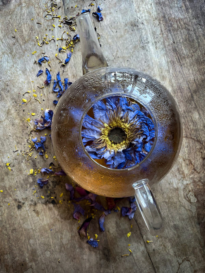 Clear glass teapot with dried flowers on a wooden surface
