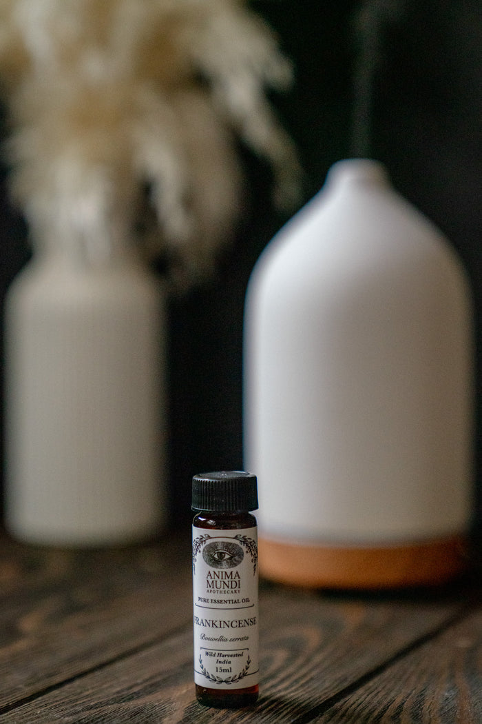Small bottle of Anima Mundi on a wooden surface with white ceramic bottles in the background.