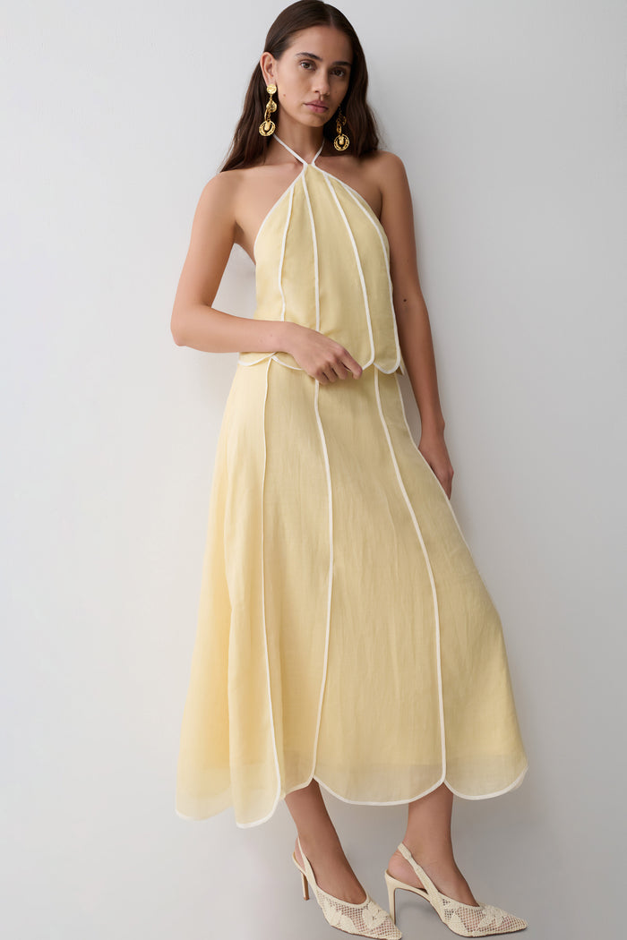 Woman wearing a light yellow panelled halter sleeveless top with matching skirt.