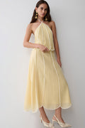 Woman wearing a light yellow panelled halter sleeveless top with matching skirt.