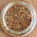 Glass jar filled with dried herbs on a wooden surface