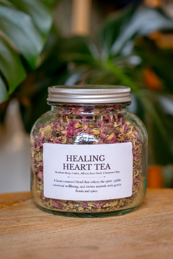 Jar of 'Healing Heart Tea' with a label on a wooden surface and plant background