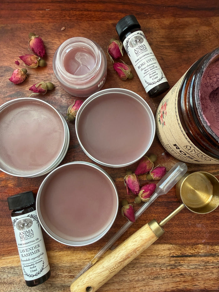 Cosmetic products including jars, bottles, and a spoon on a wooden surface with dried flowers.