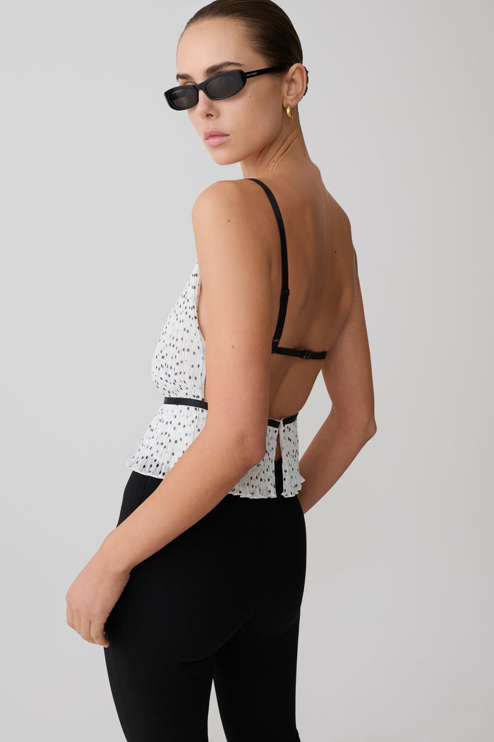 Woman wearing a black and white  pleated sleeveless top.