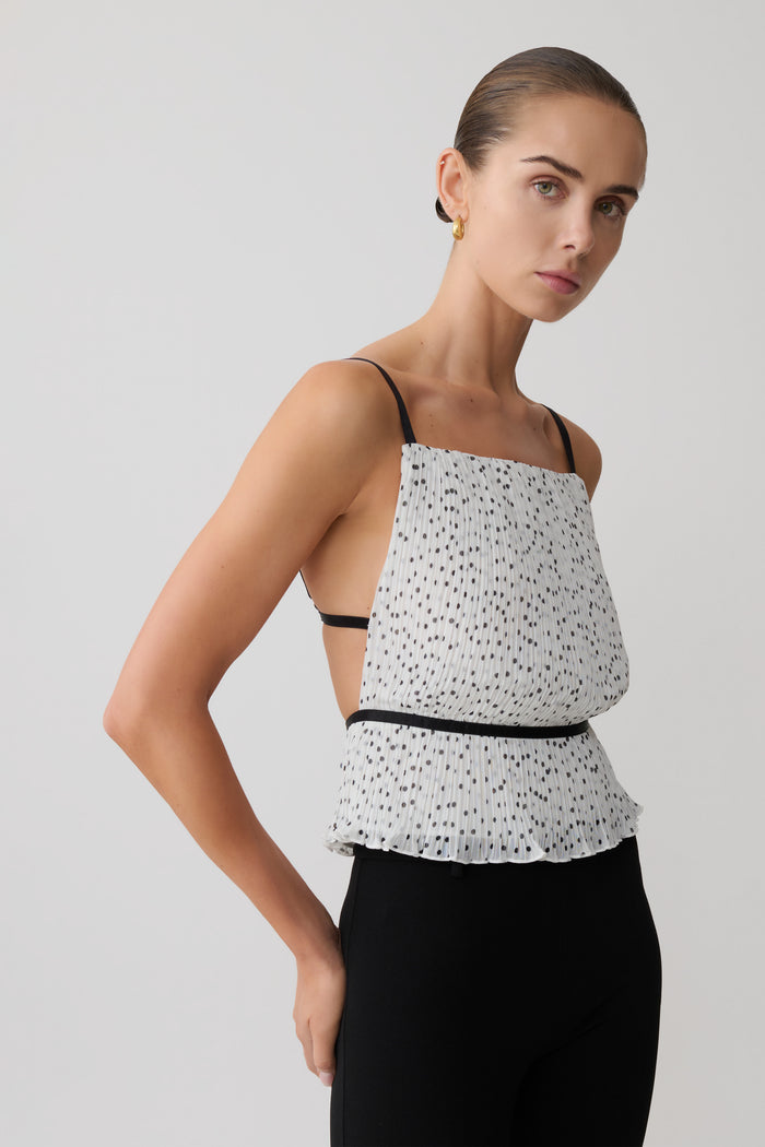 Woman wearing a pleated sleeveless polkadot top.