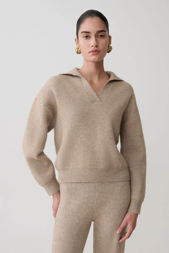 Woman in a beige collared sweater against a white background.