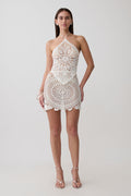 Woman wearing white crochet halter top with matching mini skirt.