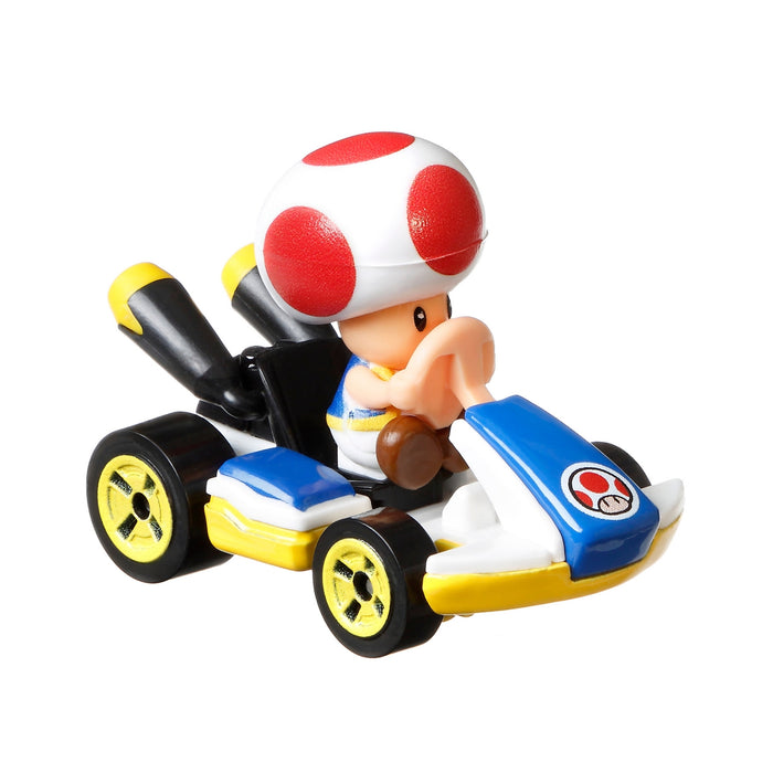 The Mattel Hot Wheels Mario Kart Replica Die Cast Vehicle features Toad in a blue and yellow go-kart with black wheels, his signature red-spotted mushroom cap, and a white front bumper—ideal for collectors.