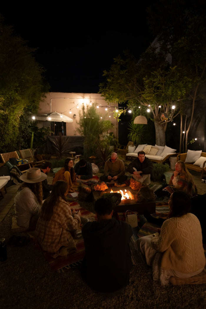 People gathered around a campfire in a backyard setting at night.