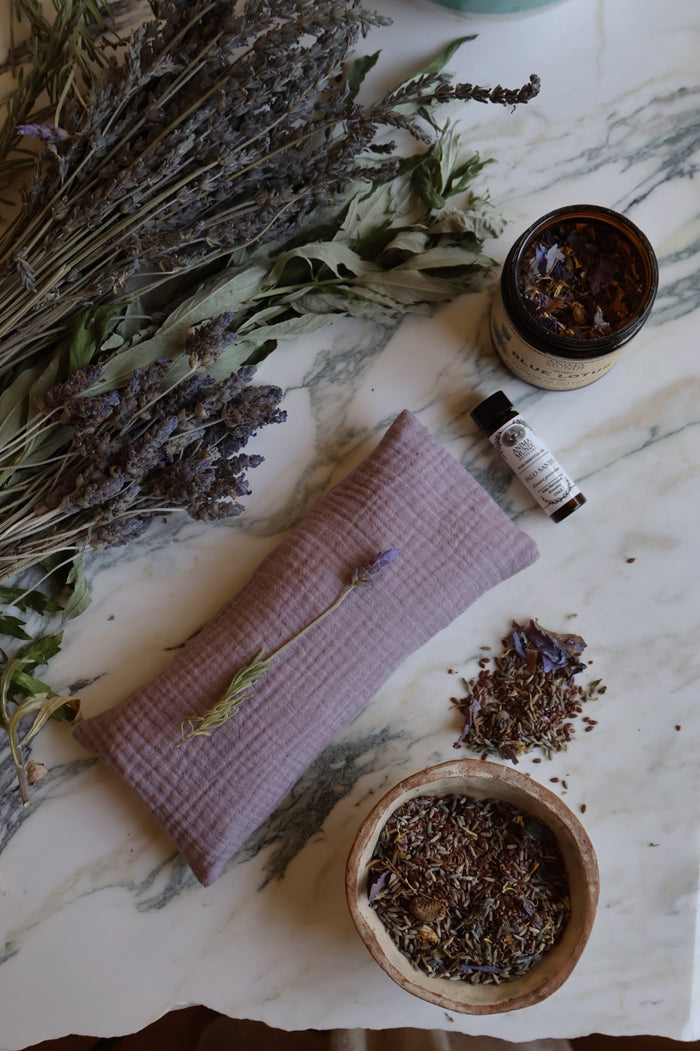 Herbal products including a jar, bottles, and dried herbs on a marble surface.