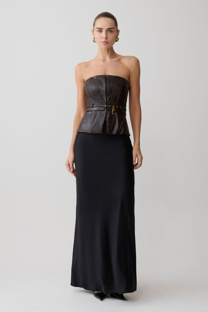 Woman wearing a strapless black evening gown with a fitted bodice and flowing skirt on a white background