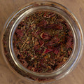 Glass jar filled with dried herbs on a wooden surface