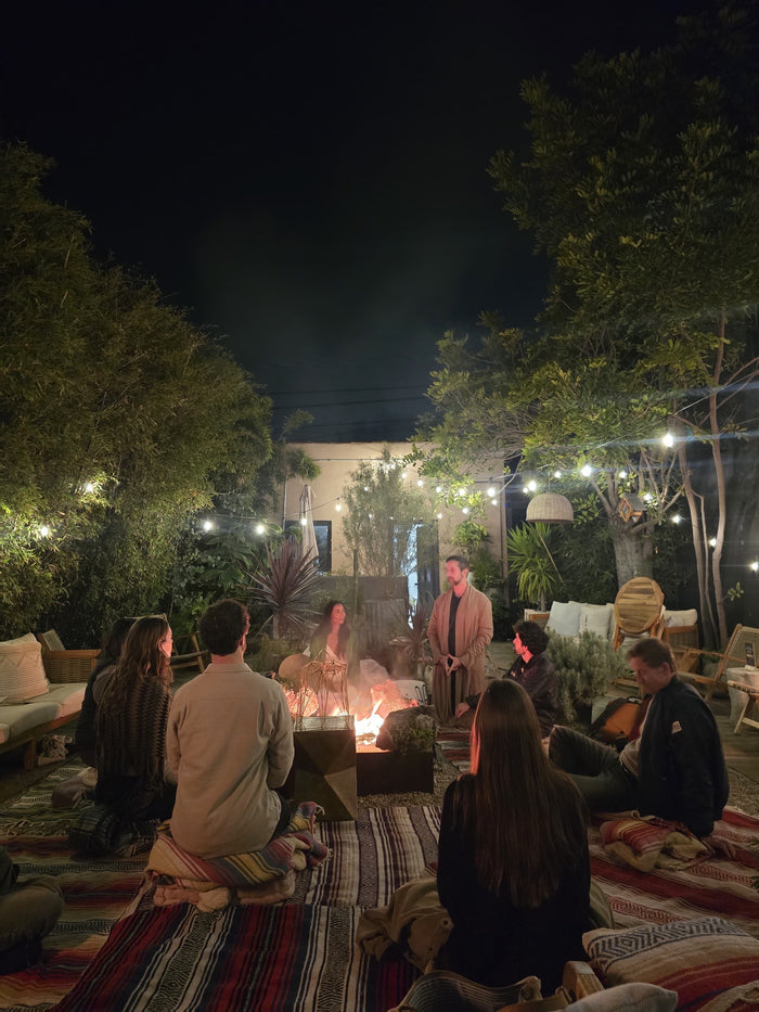 People gathered around a fire pit in a garden setting at night.