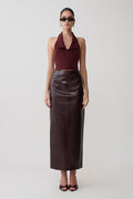 Woman wearing a burgundy halter top and dark brown leather skirt on a white background.