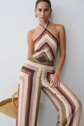 Woman wearing a striped jumpsuit against a plain background