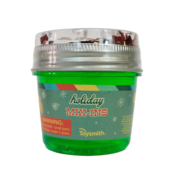 A green plastic container of Toysmith Deluxe Holiday Mix-In Slime with a silver lid and festive label, ideal for Christmas gifts or sensory play. Features snowflakes and a warning about small parts for children under three years.