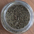 Glass jar filled with dried herbs on a wooden surface